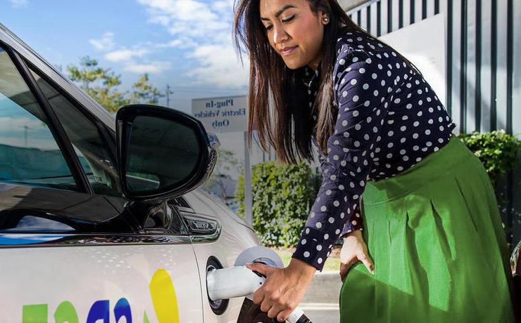 一名妇女正在给一辆电动汽车充电，也被称为电动汽车